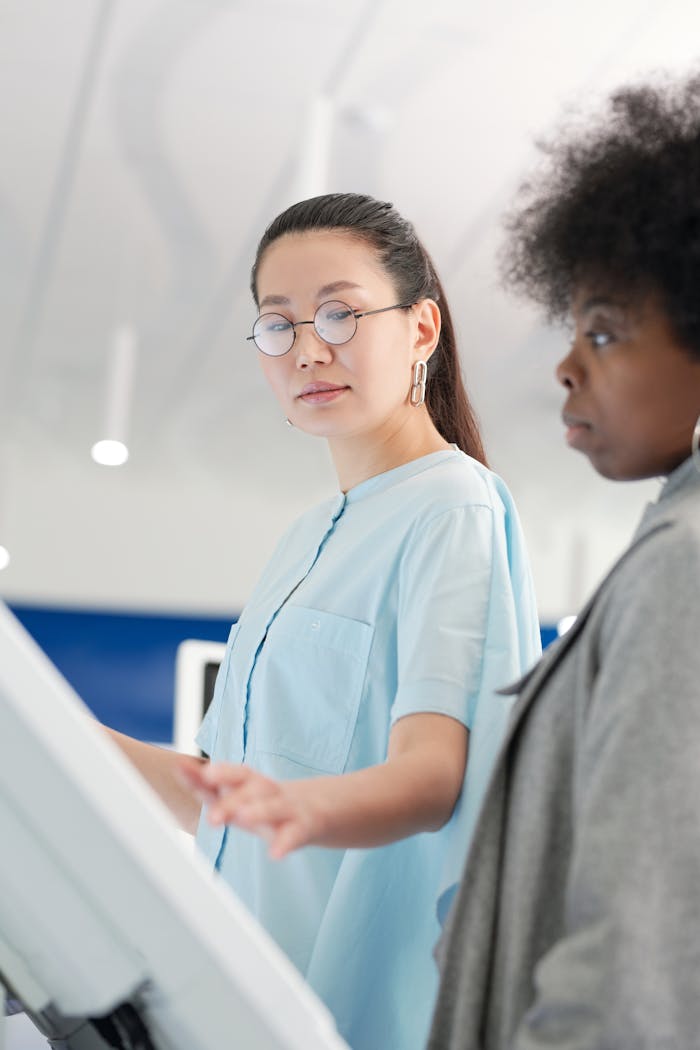 Two women interact with a touchscreen in a bright indoor setting, highlighting collaboration.